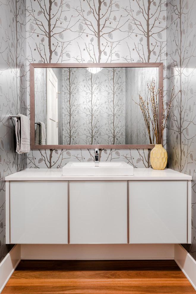Inspiration for a contemporary powder room in Vancouver with flat-panel cabinets, white cabinets, grey walls, medium hardwood floors, a drop-in sink, brown floor and white benchtops.