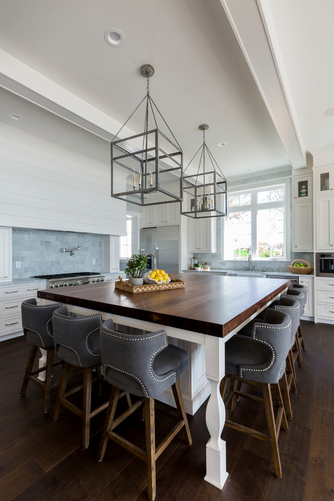 Inspiration for a large beach style l-shaped kitchen in Charlotte with an undermount sink, shaker cabinets, white cabinets, wood benchtops, grey splashback, stainless steel appliances, medium hardwood floors, with island, brown floor and brown benchtop.