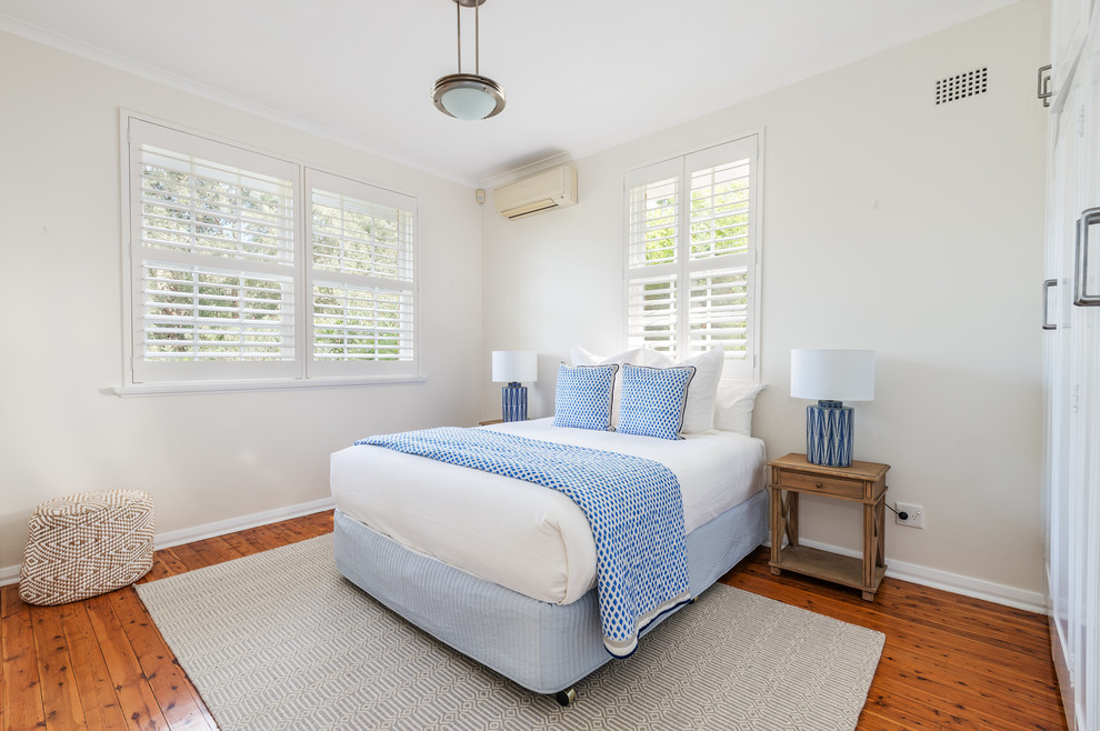 Photo of a mid-sized transitional guest bedroom in Sydney with beige walls and medium hardwood floors.