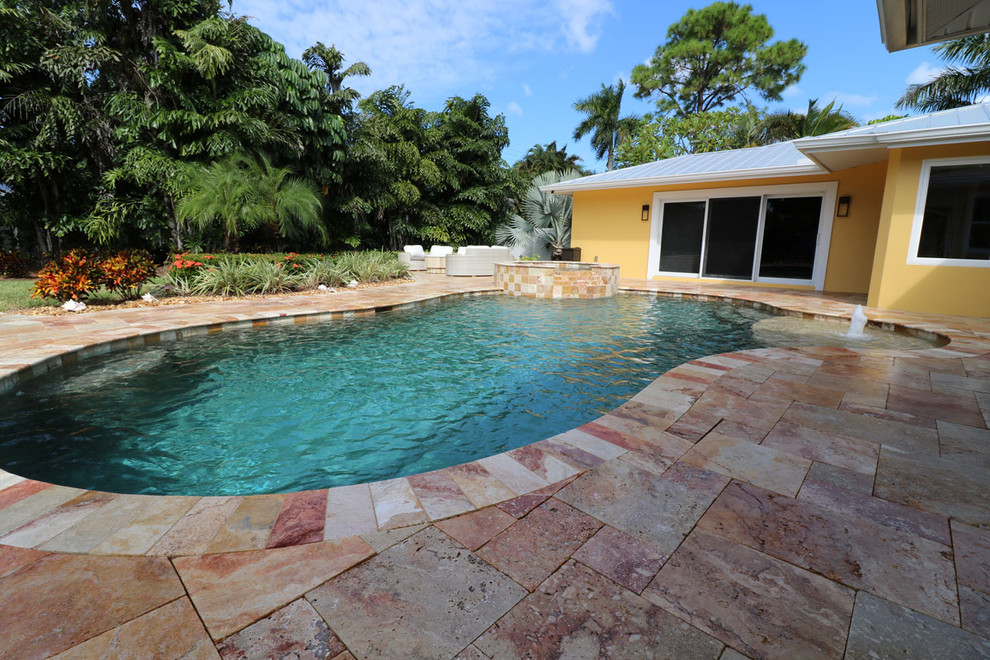 Large transitional backyard tile and custom-shaped hot tub photo in Miami