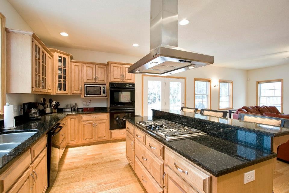 Design ideas for a large transitional l-shaped open plan kitchen in Other with a double-bowl sink, raised-panel cabinets, light wood cabinets, granite benchtops, stainless steel appliances, light hardwood floors and with island.