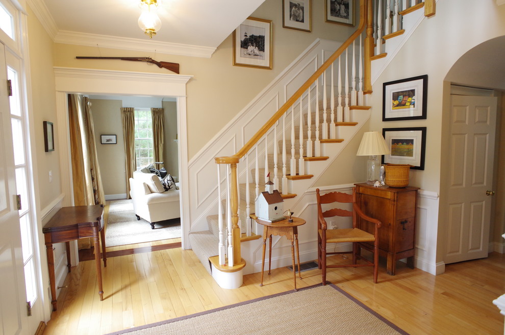 Example of a mid-sized transitional light wood floor foyer design in Boston with white walls and a white front door