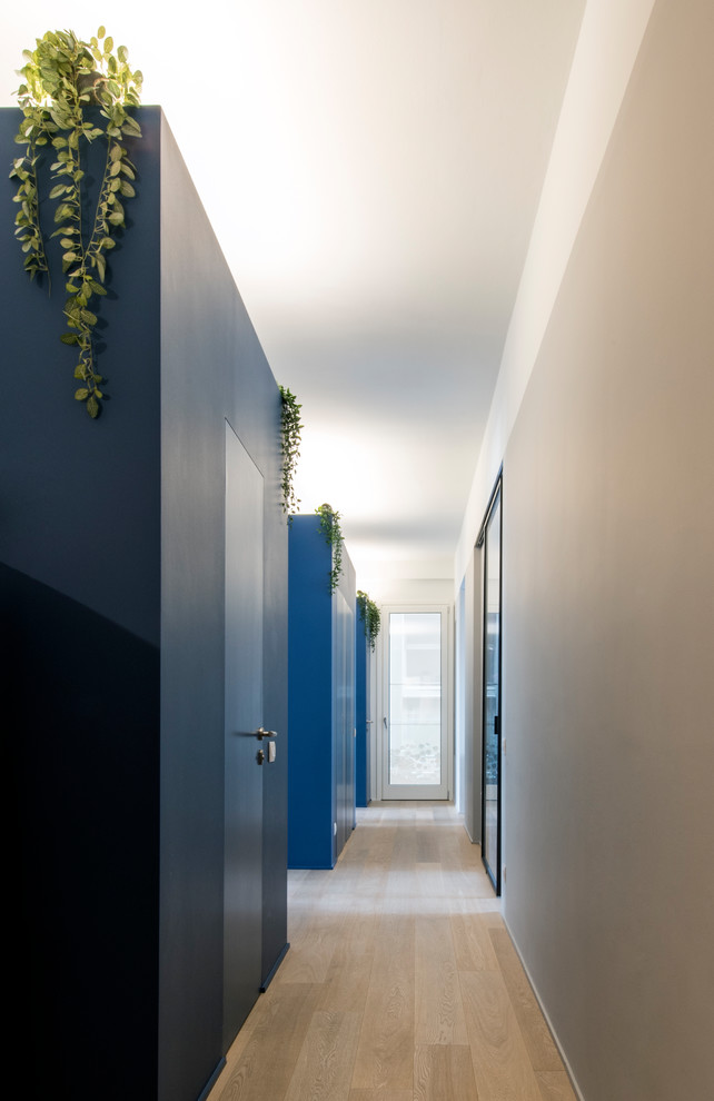 Inspiration for a large contemporary hallway in Milan with blue walls and medium hardwood floors.