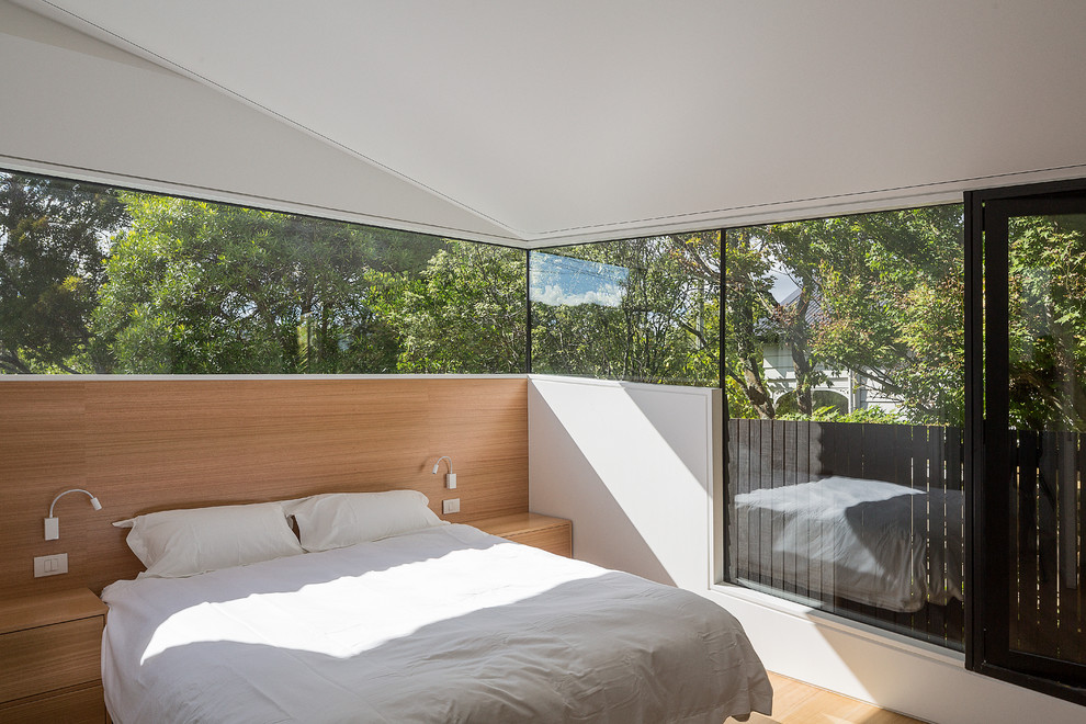 Modern bedroom in Auckland with white walls and light hardwood floors.