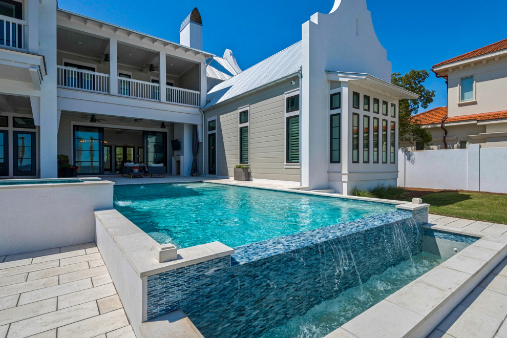 Esempio di una grande piscina a sfioro infinito stile marinaro rettangolare dietro casa con una vasca idromassaggio e pavimentazioni in pietra naturale