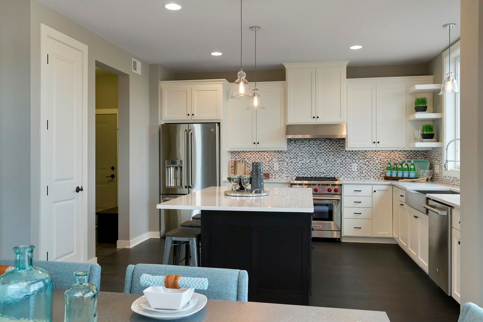 Inspiration for a mid-sized transitional l-shaped dark wood floor open concept kitchen remodel in Minneapolis with a farmhouse sink, shaker cabinets, white cabinets, quartz countertops, multicolored backsplash, mosaic tile backsplash, stainless steel appliances and an island