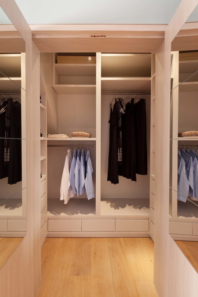 Photo of a mid-sized eclectic women's walk-in wardrobe in London with shaker cabinets, grey cabinets, light hardwood floors and grey floor.