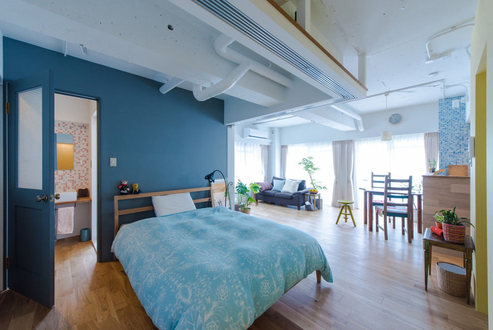 Imagen de dormitorio principal marinero de tamaño medio sin chimenea con paredes azules y suelo de madera en tonos medios