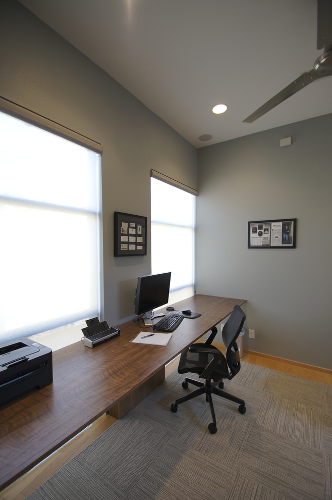Photo of a small modern home office in Austin with blue walls, light hardwood floors and a built-in desk.