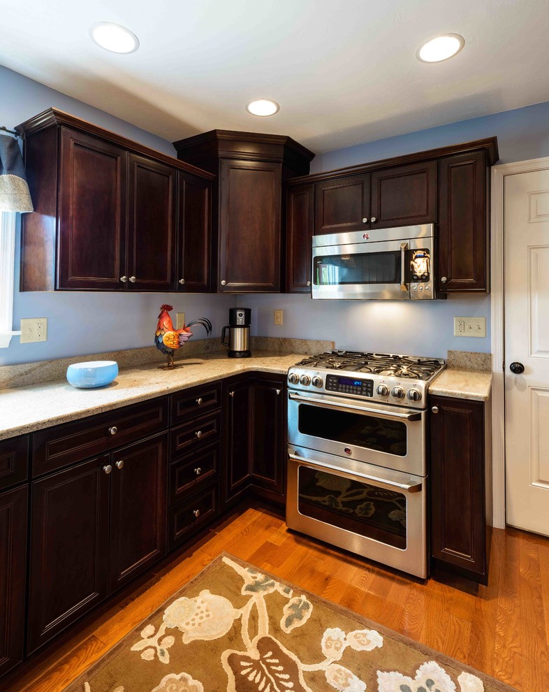 Example of a mid-sized transitional u-shaped medium tone wood floor and brown floor enclosed kitchen design with an undermount sink, beaded inset cabinets, dark wood cabinets, granite countertops, stainless steel appliances and an island