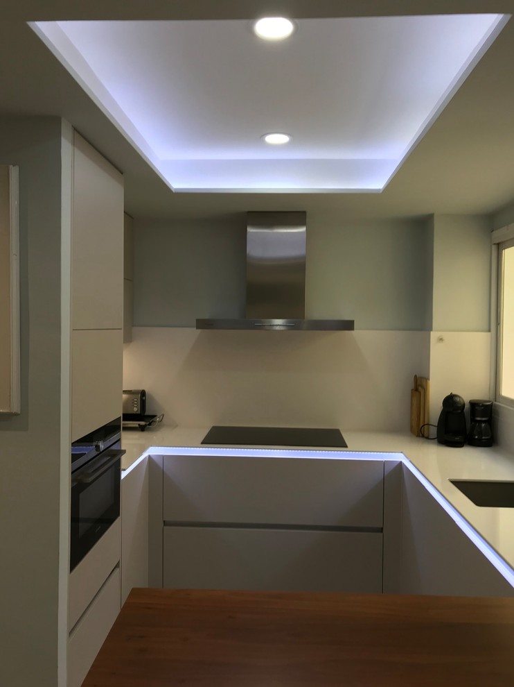 Design ideas for a small modern u-shaped separate kitchen in Madrid with an undermount sink, flat-panel cabinets, white cabinets, quartz benchtops, white splashback, stone slab splashback, stainless steel appliances, ceramic floors, a peninsula and grey floor.
