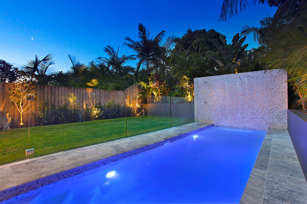 This is an example of a small contemporary backyard rectangular lap pool in Sydney with natural stone pavers and a hot tub.