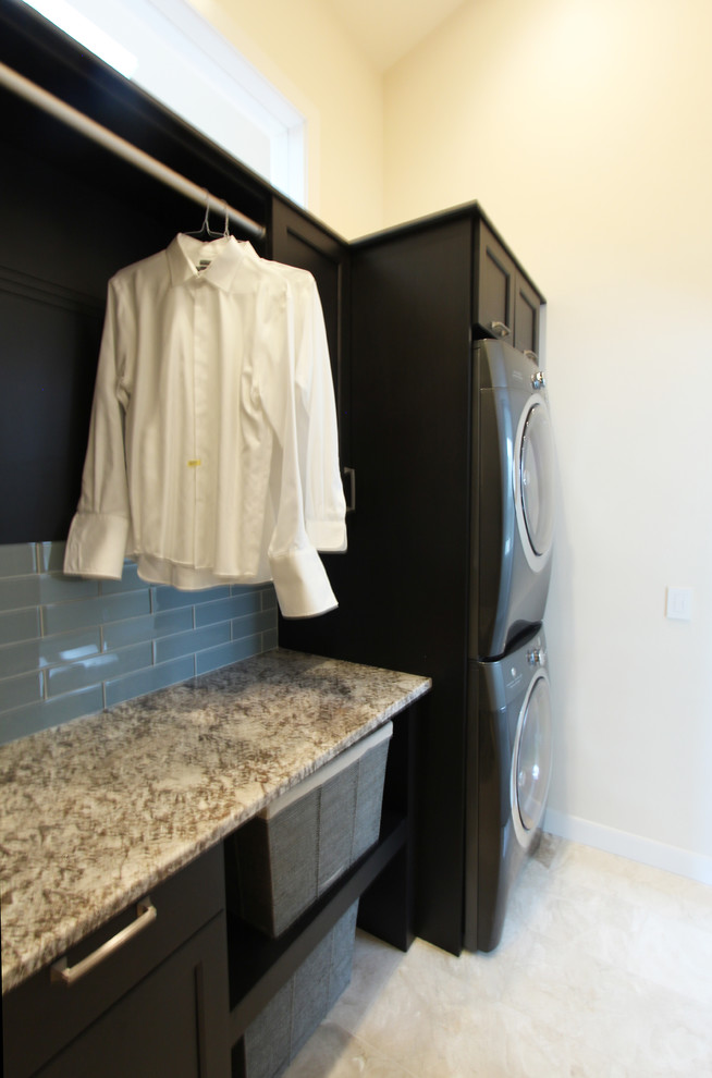 Small transitional single-wall utility room in Other with recessed-panel cabinets, dark wood cabinets, granite benchtops, beige walls, travertine floors, a side-by-side washer and dryer, beige floor and beige benchtop.