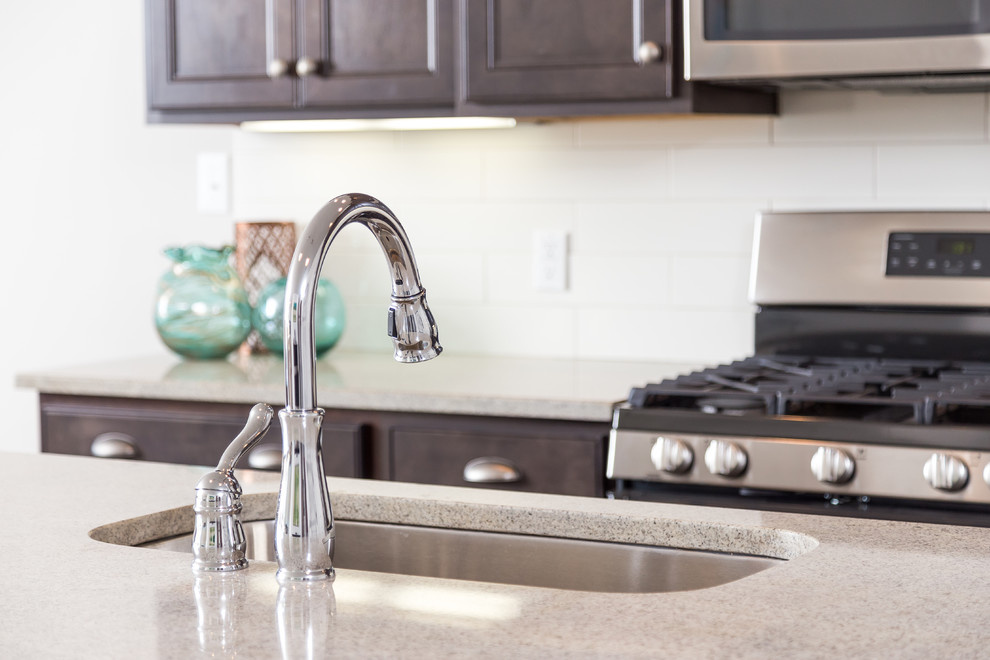 Mid-sized transitional single-wall medium tone wood floor eat-in kitchen photo with an undermount sink, shaker cabinets, dark wood cabinets, granite countertops, white backsplash, subway tile backsplash, stainless steel appliances and an island