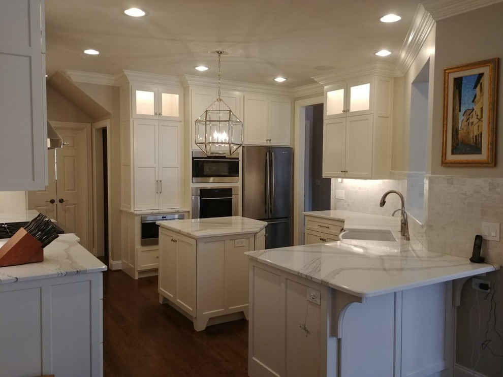 Large transitional single-wall dark wood floor and brown floor enclosed kitchen photo in Nashville with a farmhouse sink, recessed-panel cabinets, white cabinets, quartzite countertops, white backsplash, subway tile backsplash, stainless steel appliances, an island and white countertops