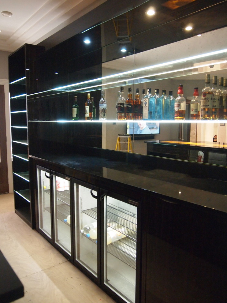 This is an example of a large contemporary home bar in Surrey with open cabinets, dark wood cabinets and onyx benchtops.