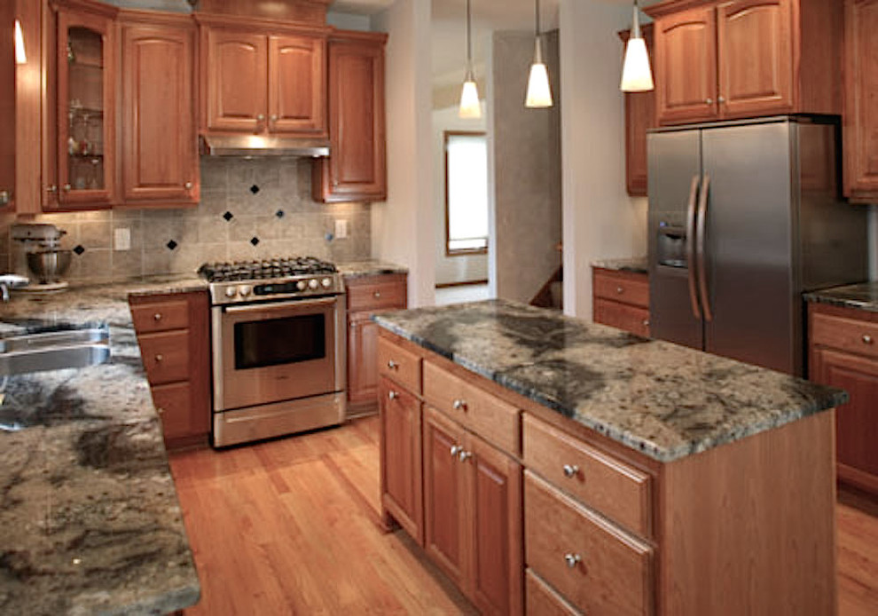 Enclosed kitchen - mid-sized transitional u-shaped medium tone wood floor enclosed kitchen idea in Miami with a double-bowl sink, raised-panel cabinets, medium tone wood cabinets, granite countertops, gray backsplash, ceramic backsplash, stainless steel appliances and an island