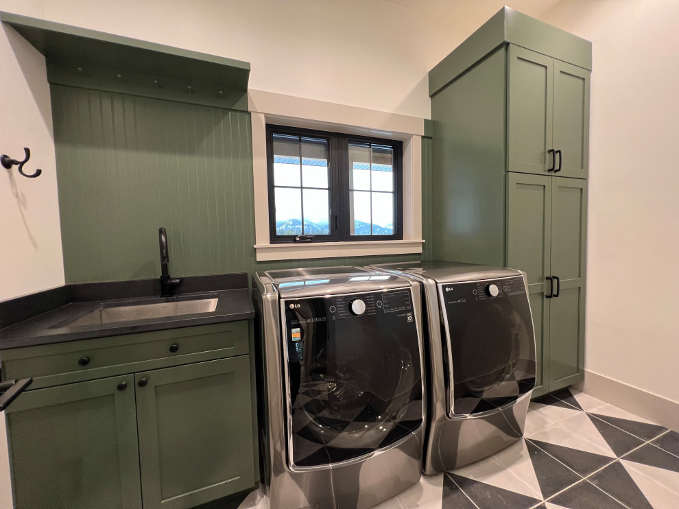 This is an example of a mid-sized transitional dedicated laundry room in Other with an undermount sink, green cabinets, quartz benchtops, green splashback, timber splashback, beige walls, ceramic floors, a side-by-side washer and dryer, black benchtop and shaker cabinets.