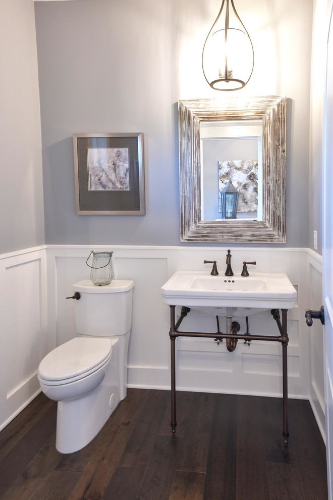 Inspiration for a traditional powder room with a two-piece toilet, grey walls, dark hardwood floors, a console sink, brown floor, white benchtops, a freestanding vanity and decorative wall panelling.