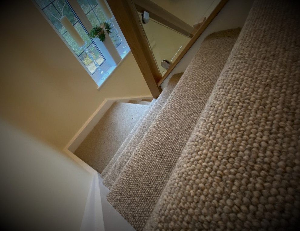 Inspiration for a large country carpeted curved staircase in Hertfordshire with carpet risers and wood railing.