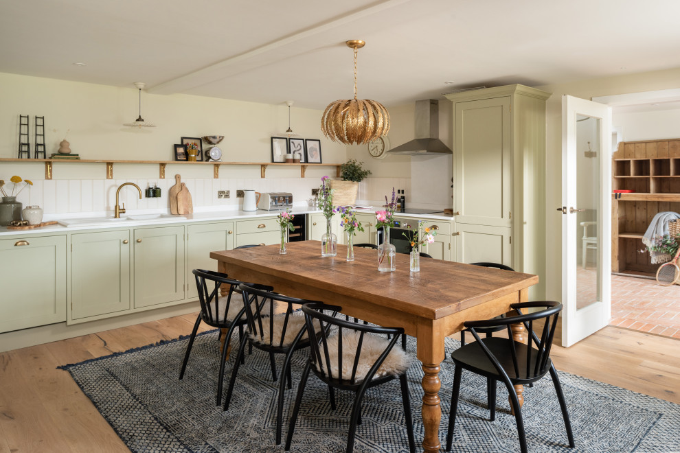 Inspiration for a medium sized rural kitchen/diner in Gloucestershire with a built-in sink, recessed-panel cabinets, green cabinets, granite worktops, stainless steel appliances, medium hardwood flooring, a breakfast bar and white worktops.