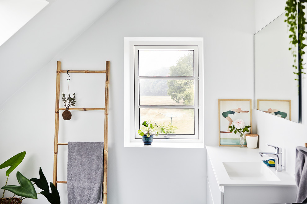Scandinavian bathroom in Aarhus with flat-panel cabinets, white cabinets, white walls and an integrated sink.