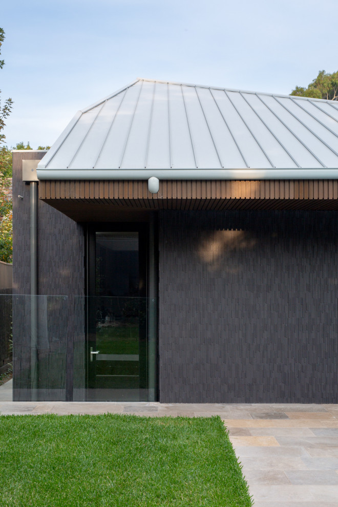 Photo of a large contemporary one-storey black exterior in Melbourne with mixed siding and a flat roof.