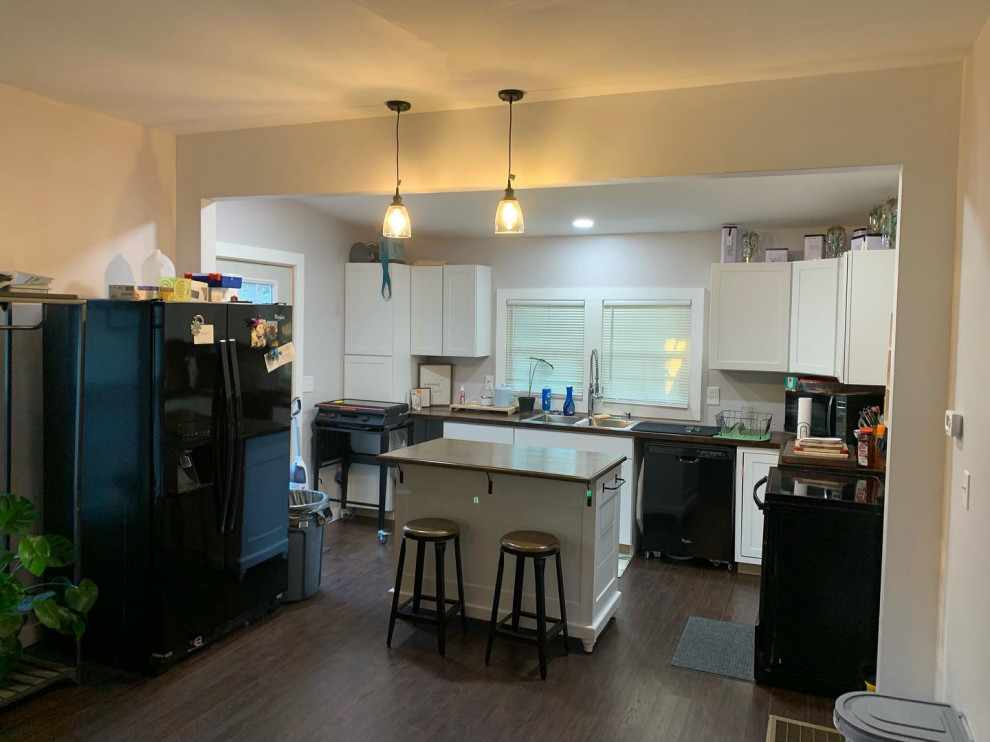 Example of a transitional l-shaped brown floor open concept kitchen design with a double-bowl sink, shaker cabinets, white cabinets, an island and brown countertops