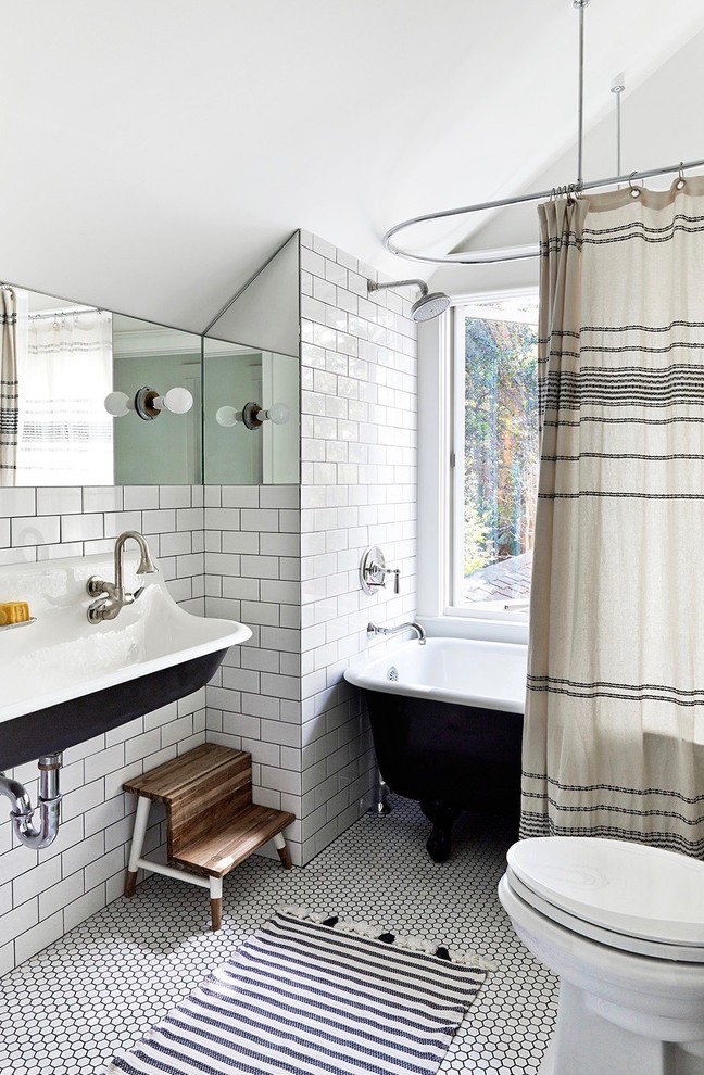 This is an example of a beach style bathroom in Los Angeles with a claw-foot tub, a shower/bathtub combo, white tile, subway tile, white walls, a trough sink, white floor and a shower curtain.
