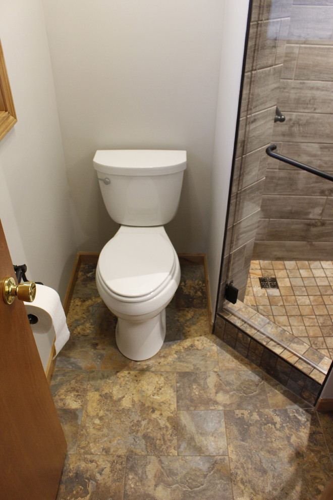 Photo of a small 3/4 bathroom in Other with raised-panel cabinets, light wood cabinets, a corner shower, a two-piece toilet, vinyl floors, a drop-in sink and tile benchtops.
