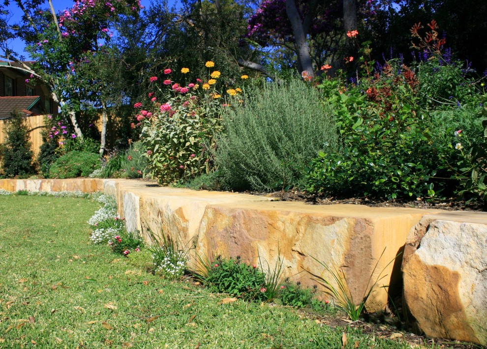 Design ideas for a traditional front yard garden in Sydney with a retaining wall and natural stone pavers.