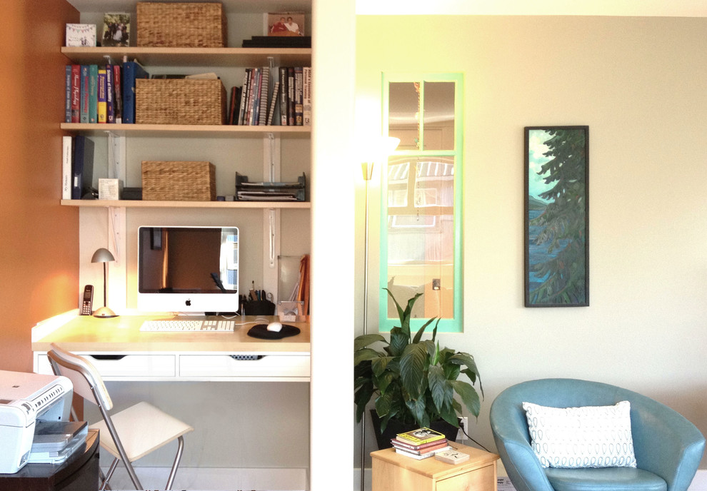 Photo of a small contemporary home office in Calgary with orange walls and a built-in desk.