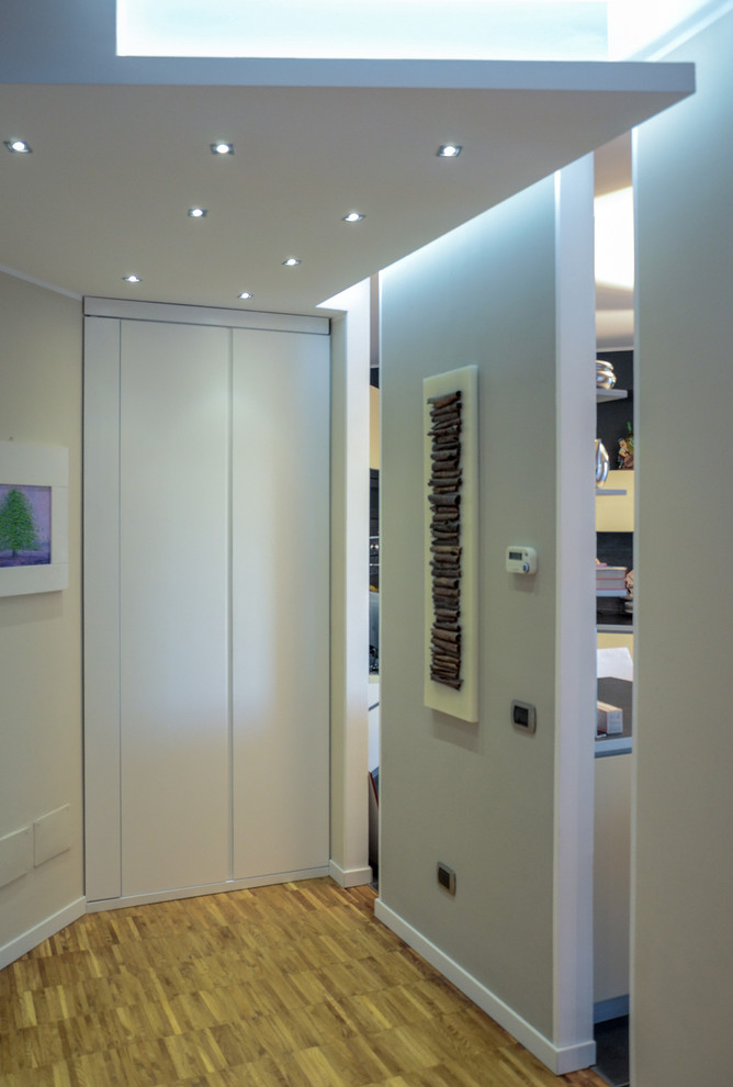 Photo of a mid-sized contemporary hallway in Milan with beige walls and light hardwood floors.