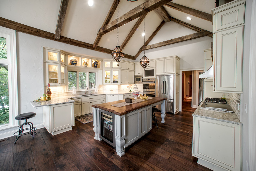 Photo of a traditional u-shaped kitchen in Milwaukee with beaded inset cabinets, beige cabinets, wood benchtops, white splashback, stainless steel appliances, medium hardwood floors and with island.