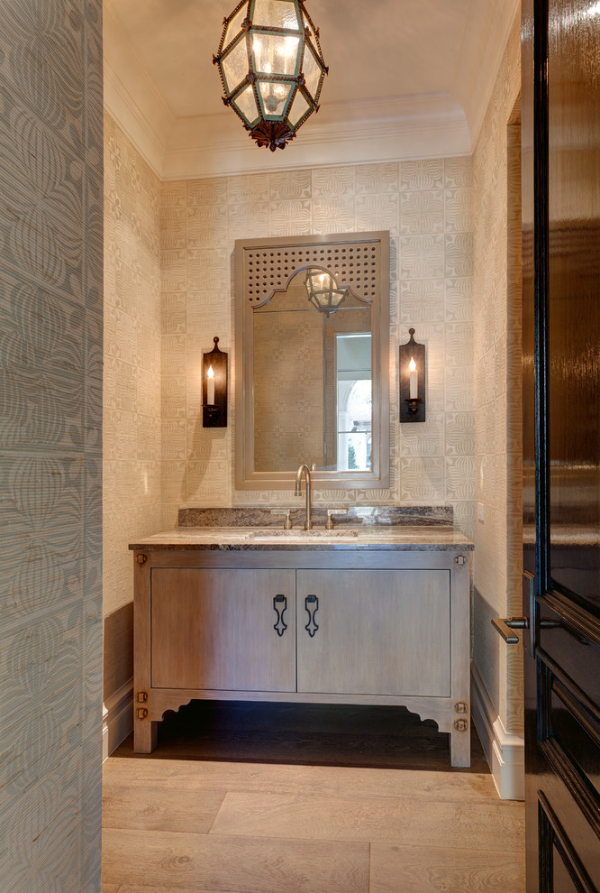 This is an example of a mediterranean powder room in Dallas with an undermount sink, furniture-like cabinets, grey cabinets, beige walls, medium hardwood floors and grey benchtops.