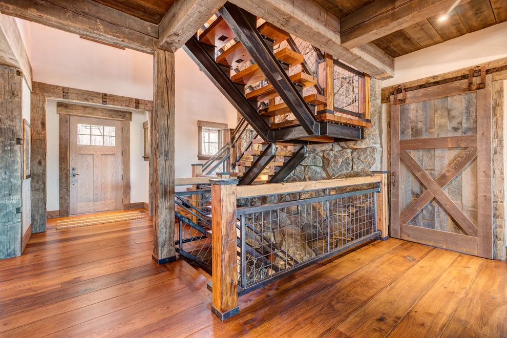 Photo of a country wood staircase in Other with open risers and metal railing.