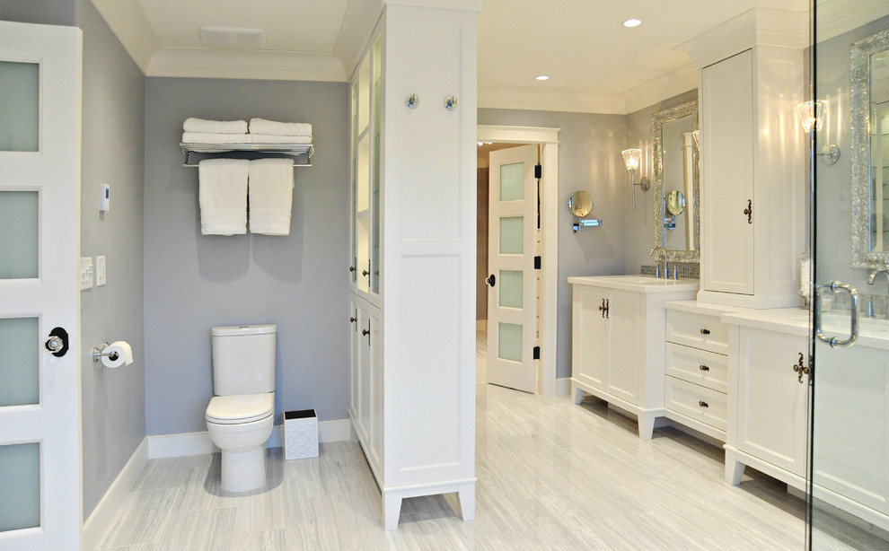 This is an example of a mid-sized traditional master bathroom in Vancouver with white cabinets, recessed-panel cabinets, a freestanding tub, a two-piece toilet, white tile, stone tile, marble floors, an undermount sink, engineered quartz benchtops and grey walls.