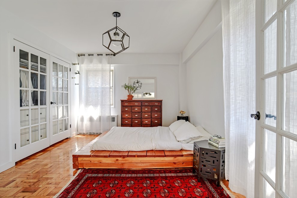 This is an example of a mid-sized transitional master bedroom in New York with white walls, medium hardwood floors, no fireplace and brown floor.