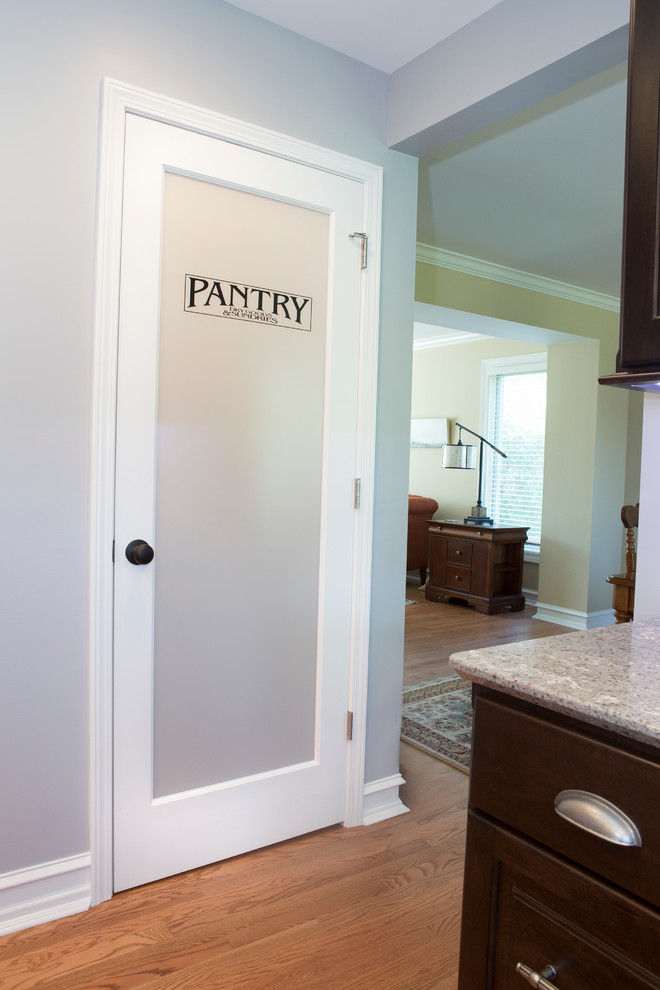 Enclosed kitchen - mid-sized transitional u-shaped light wood floor enclosed kitchen idea in Chicago with an undermount sink, raised-panel cabinets, dark wood cabinets, quartz countertops, beige backsplash, ceramic backsplash, stainless steel appliances and an island