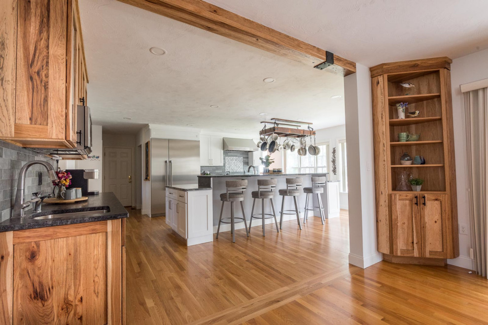 Large transitional single-wall light wood floor and brown floor eat-in kitchen photo in Boston with a farmhouse sink, shaker cabinets, white cabinets, granite countertops, gray backsplash, ceramic backsplash, stainless steel appliances, an island and gray countertops