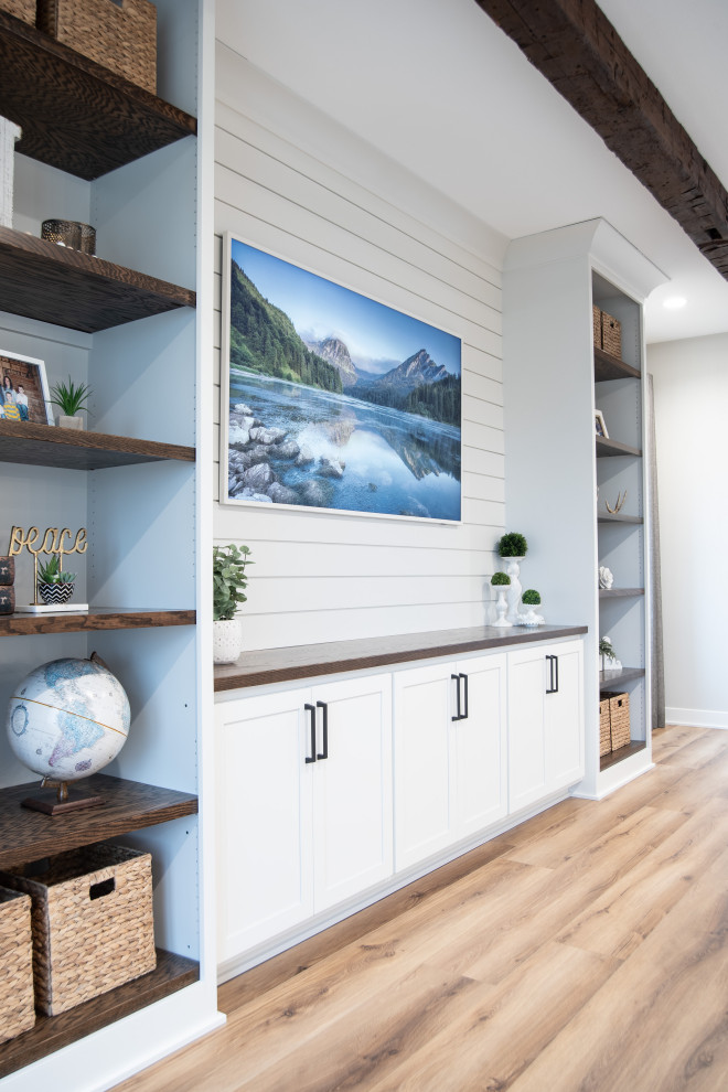 Cette image montre une salle de séjour rustique ouverte avec un mur blanc, un téléviseur encastré, poutres apparentes, du lambris de bois et un sol en vinyl.