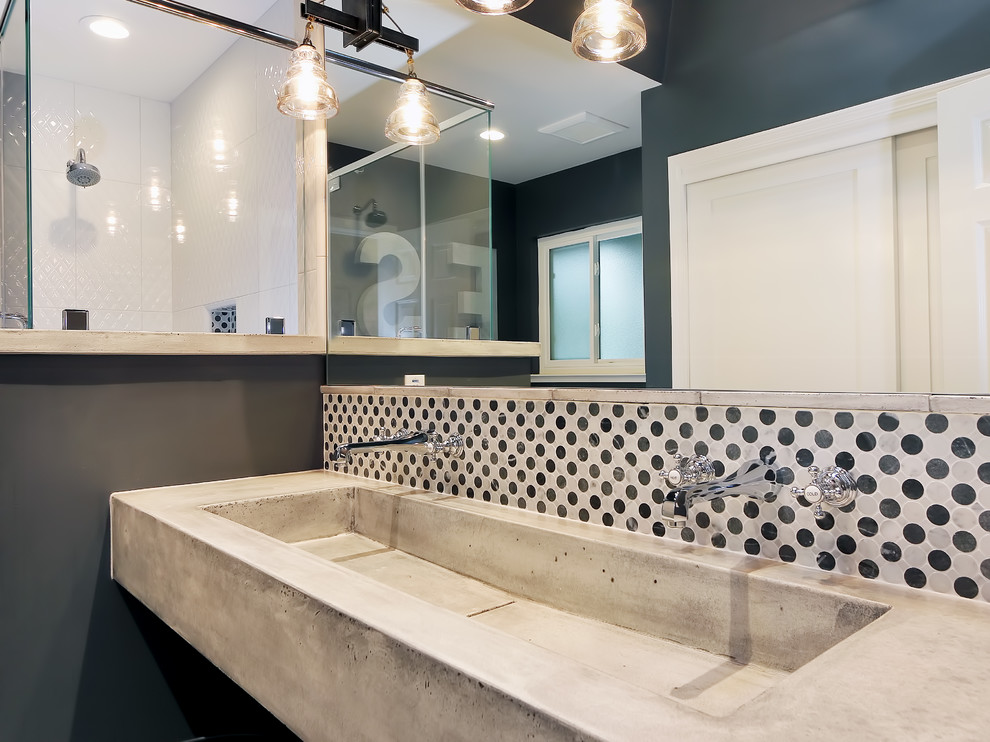 This is an example of a mid-sized industrial kids bathroom in San Francisco with an integrated sink, concrete benchtops, an alcove tub, a shower/bathtub combo, a one-piece toilet, white tile, stone tile, grey walls, ceramic floors, grey floor, a hinged shower door and grey benchtops.