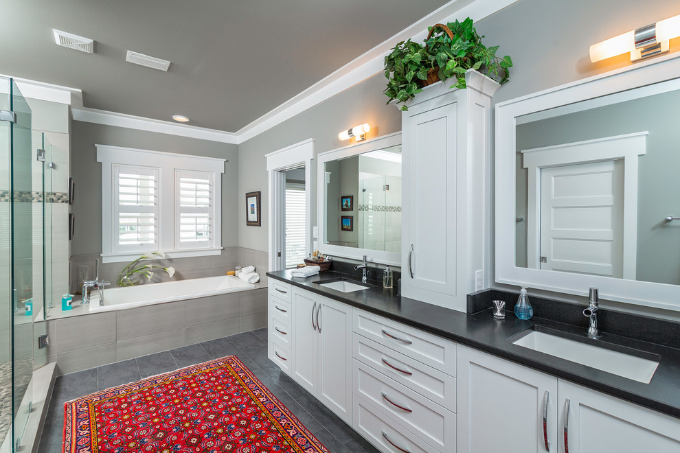 Design ideas for a mid-sized beach style master bathroom in Atlanta with an undermount sink, shaker cabinets, white cabinets, solid surface benchtops, an alcove shower, a one-piece toilet, white tile, porcelain tile, white walls and porcelain floors.