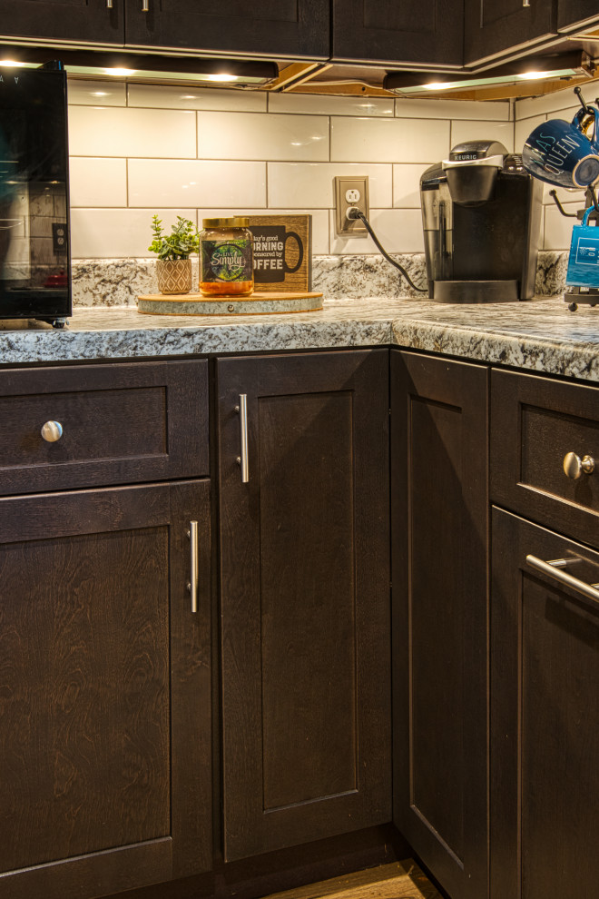 Example of a mid-sized transitional u-shaped light wood floor and brown floor open concept kitchen design with a drop-in sink, shaker cabinets, gray cabinets, laminate countertops, white backsplash, subway tile backsplash, stainless steel appliances, a peninsula and white countertops