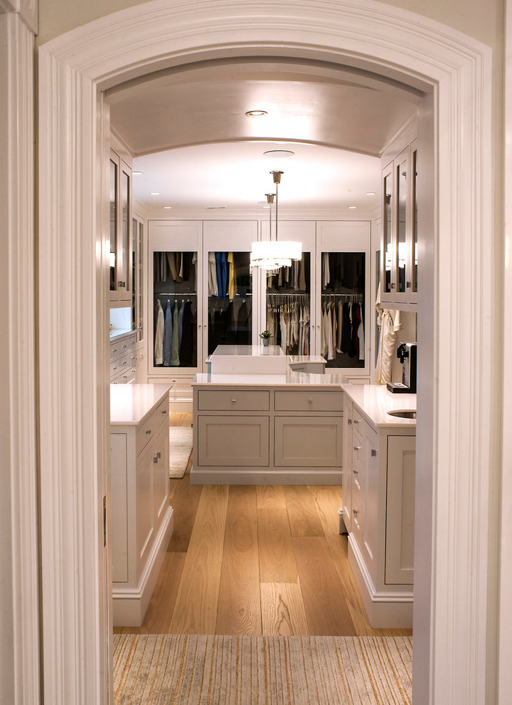 Large transitional dressing room in Boston with shaker cabinets, beige cabinets and laminate floors.
