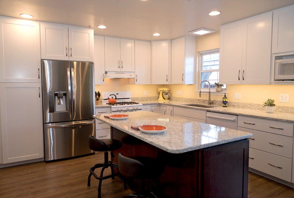 Design ideas for a mid-sized transitional l-shaped eat-in kitchen in Baltimore with an undermount sink, shaker cabinets, white cabinets, quartz benchtops, beige splashback, stainless steel appliances, medium hardwood floors, with island and brown floor.