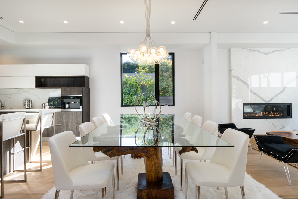 Inspiration for a contemporary open plan dining in Los Angeles with white walls, light hardwood floors, a ribbon fireplace and beige floor.