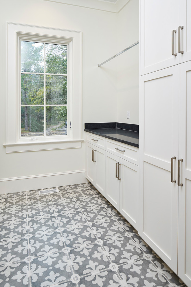 Inspiration for a mid-sized transitional u-shaped dedicated laundry room in Charleston with an undermount sink, shaker cabinets, white cabinets, soapstone benchtops, white walls, ceramic floors, a side-by-side washer and dryer, multi-coloured floor and black benchtop.