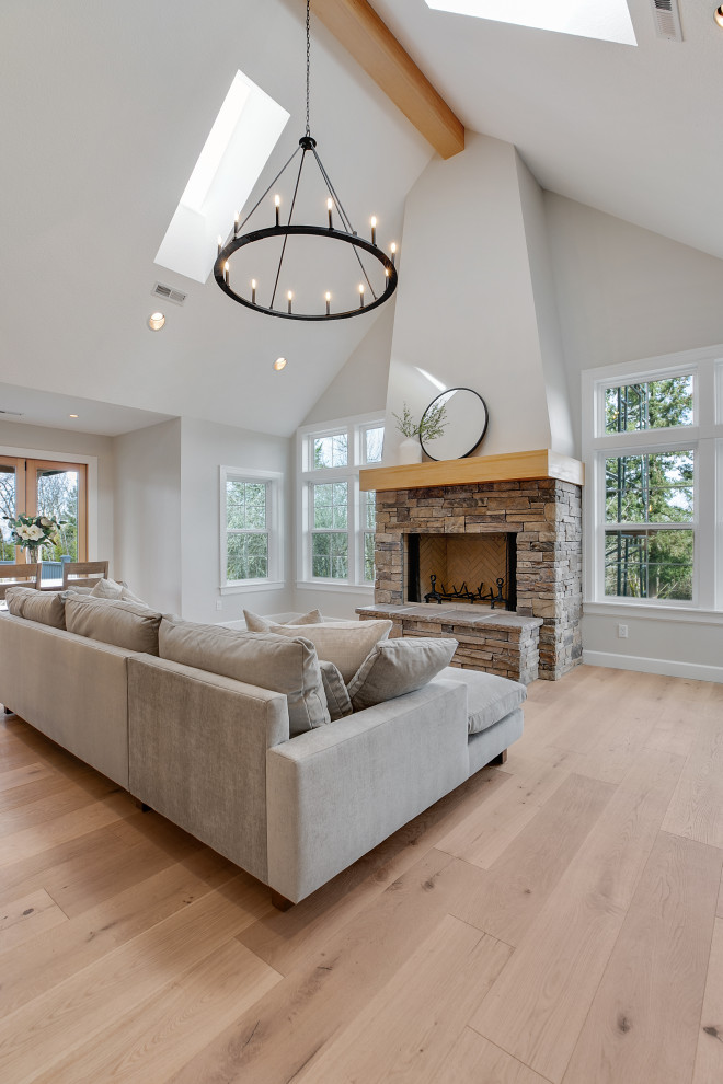 Photo of an expansive classic open plan living room in Portland with light hardwood flooring, brown floors, grey walls, a wood burning stove, a stacked stone fireplace surround, a vaulted ceiling, a home bar and no tv.