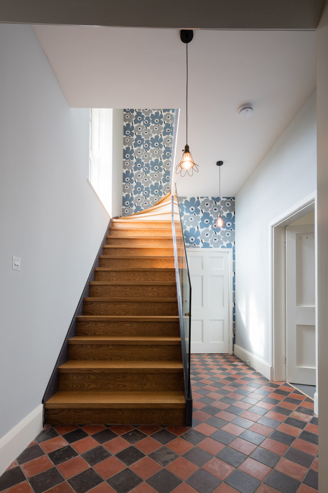 This is an example of a mid-sized contemporary wood l-shaped staircase in Wiltshire with wood risers and glass railing.
